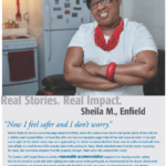 Sheila M., an older African-American woman, smiling and wearing glasses, standing in a kitchen.